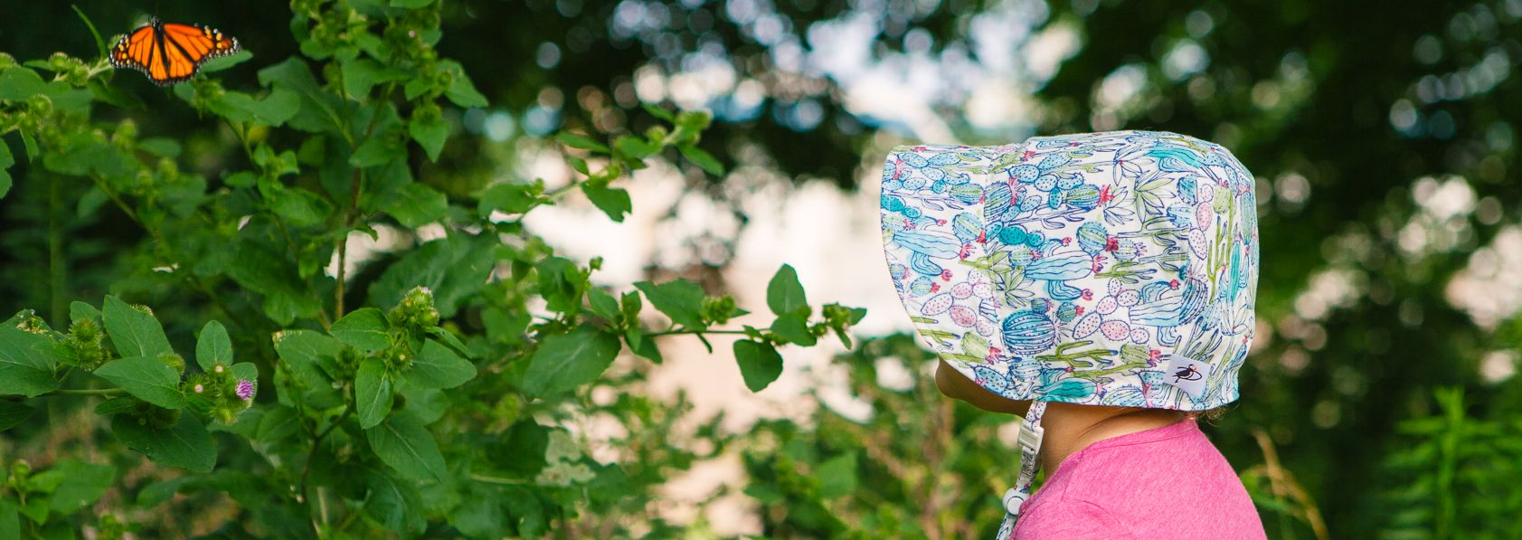 Toddler and Infant UPF50 Sun Protection Bonnets in Linen, Cotton Prints, Organic Cotton or Cotton Oxford Cotton-Made in Canada by Puffin Gear-toddler watching a monarch butterfly
